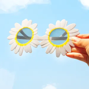 Occhiali da sole a margherita per bambini tenuti contro un cielo azzurro limpido