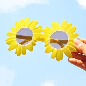 Primo piano di occhiali da festa a girasole giallo brillante su sfondo cielo blu.