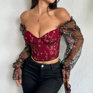 Detailed view of burgundy embroidered corset top with sheer black mesh sleeves.