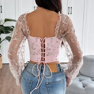 Back view detail of pink embroidered mesh top with lace-up design and floral patterns