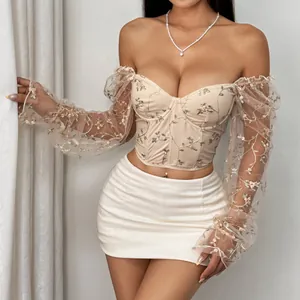 Detailed macro view of an apricot floral embroidered mesh long sleeve corset top
