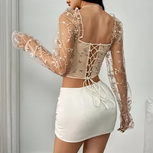 Detailed back view of a beige corset top featuring floral embroidered sheer long sleeves.