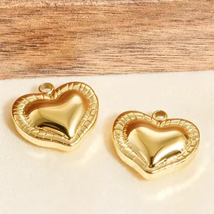 Nahaufnahme von zwei goldenen 3D-Herzanhängern mit Strukturrand auf Stoff und Holz
