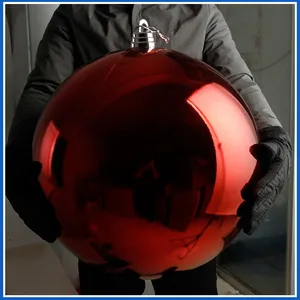 Große glänzende rote Weihnachtskugel in den Händen zur Darstellung der gewaltigen Größe