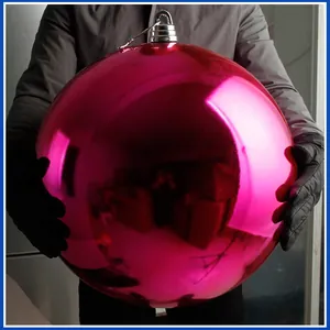 Nahaufnahme einer riesigen glänzenden rosa Weihnachtskugel in den Händen für Maßstab