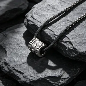 Pendentif cylindre mantra six mots en acier titane rétro sur fond de pierre sombre