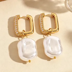 Close-up detail of gold rectangular hoop earrings with baroque pearls and pave stones
