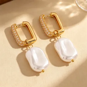 Detailed view of gold rectangular hoop earrings with baroque pearl drops and pave stones.