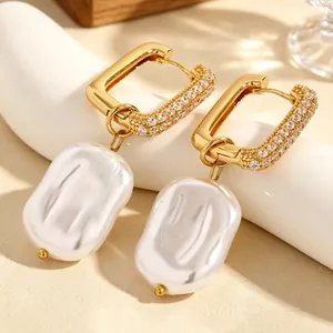 Detailed view of gold rectangular hoop earrings with sparkling crystals and pearls