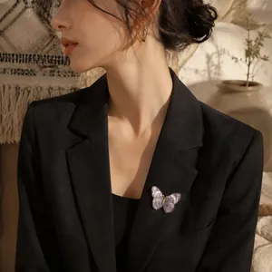 Close-up of vintage embroidered butterfly brooch on black blazer with a dreamy purple hue.