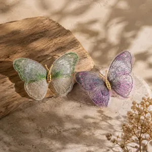 Detailed view of dreamy embroidered butterfly brooches in green and purple with gold bodies