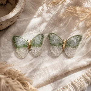 Detail view of green gradient embroidered butterfly brooches on linen