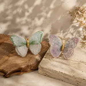 Detail shot showing exquisite embroidered butterfly brooches in green and pink hues