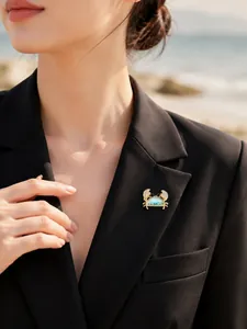 Detailed view of a mini ocean-themed crab brooch with blue stones on a black blazer.