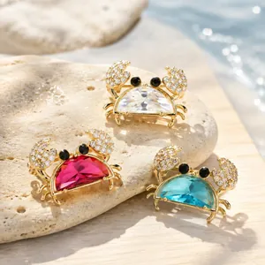 Macro view of three mini crab brooches with sparkling colorful crystals on a stone