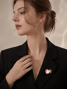 Détail d'une broche en forme de litchi en émail rouge et blanc sur un blazer noir