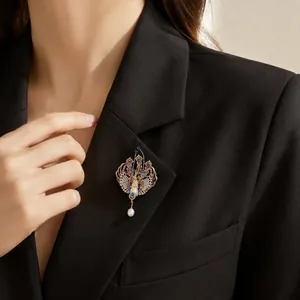 Dettaglio ravvicinato di una spilla a fenice colorata con perla su un blazer nero elegante