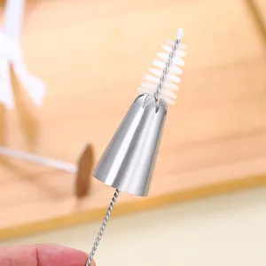 Gros plan d'une brosse en nylon nettoyant une douille à pâtisserie en acier inox