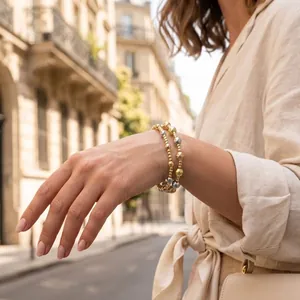 Elegant three-tone metallic beaded stretch bracelet worn on a woman's wrist in a street setting.