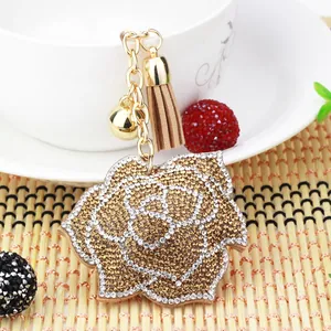 Dettaglio di un elegante portachiavi a rosa con strass dorati e bianchi e nappa