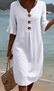Detail of white cotton linen V-neck dress with large wooden buttons and ruffled sleeves