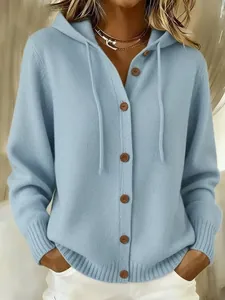 Detailansicht der weichen Textur und braunen Knöpfe der hellblauen Strickjacke mit Kapuze