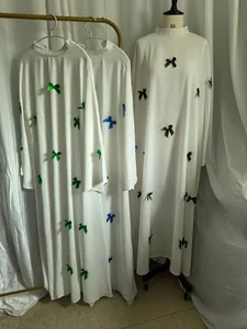 Detail view of long white plus size dresses featuring colorful ribbon bow accents