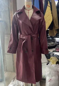 Detail view of a professional mid-length burgundy faux leather trench coat with belt