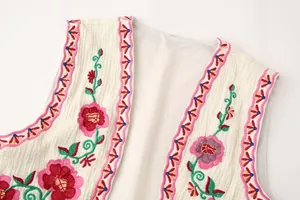 Primer plano de bordados florali y bordes geométricos en un chaleco blanco bordado