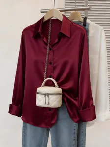 Vista dettagliata della lussuosa camicia di raso bordeaux con consistenza setosa e bottoni