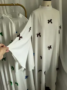 Close-up detail of white long sleeve dress featuring flared bell sleeves and bow decorations