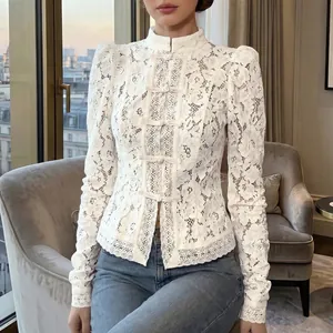 Detalle de camisa de encaje blanco con cuello alto y mangas abullonadas.