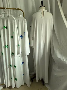 Detail view of white plus size maxi dress with colorful bow accents and flare sleeves