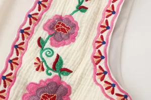 Primer plano del bordado floral de colores en un elegante chaleco blanco con textura