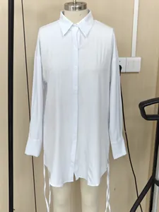 Gedetailleerd overzicht van witte blouse met lange mouwen en trekkoorden aan de zijkant.