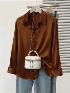 Elegante camicetta in raso marrone a maniche lunghe con borsa bianca trapuntata.