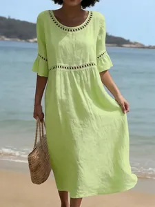 Detalle de un vestido de lino verde lima con encaje calado en una playa mediterránea