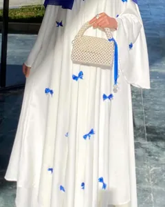 Close-up of white plus size flare sleeve dress with blue bow knot decorations.