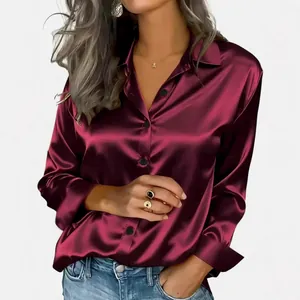 Close-up detail of elegant glossy burgundy satin long sleeve shirt featuring black buttons