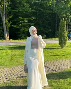 Full-length view of a cream modest two-piece set with long cardigan and skirt in a park.