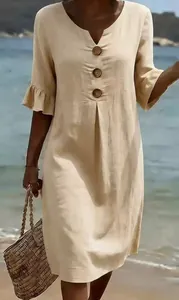 Detail view of a beige cotton linen V-neck dress with ruffle sleeves at the beach
