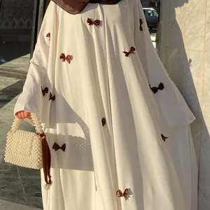 Close-up detail of a white oversized maxi dress with brown bows and flared sleeves.