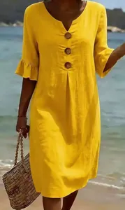 Detailed shot of yellow cotton linen V-neck dress with large wooden buttons and ruffle sleeves