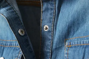 Détails des boutons-pression en métal et des coutures sur une chemise en jean bleue