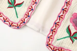 Detalle macro que muestra bordados florales intrincados y bordes festoneados en un chaleco
