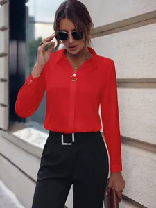 Camisa roja de manga larga para mujer con broche dorado para un look profesional