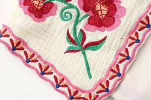 Primer plano del vibrante bordado floral en un chaleco de color crema