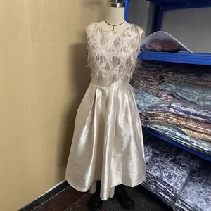 Champagne satin evening gown with sequin fringe on mannequin in warehouse setting