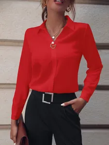 Vista detallada de una blusa roja de manga larga con un elegante broche decorativo de perla.
