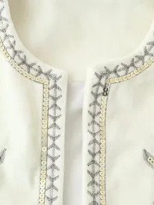 Dettaglio macro del gilet in velluto bianco con paillettes argento e ricamo grigio